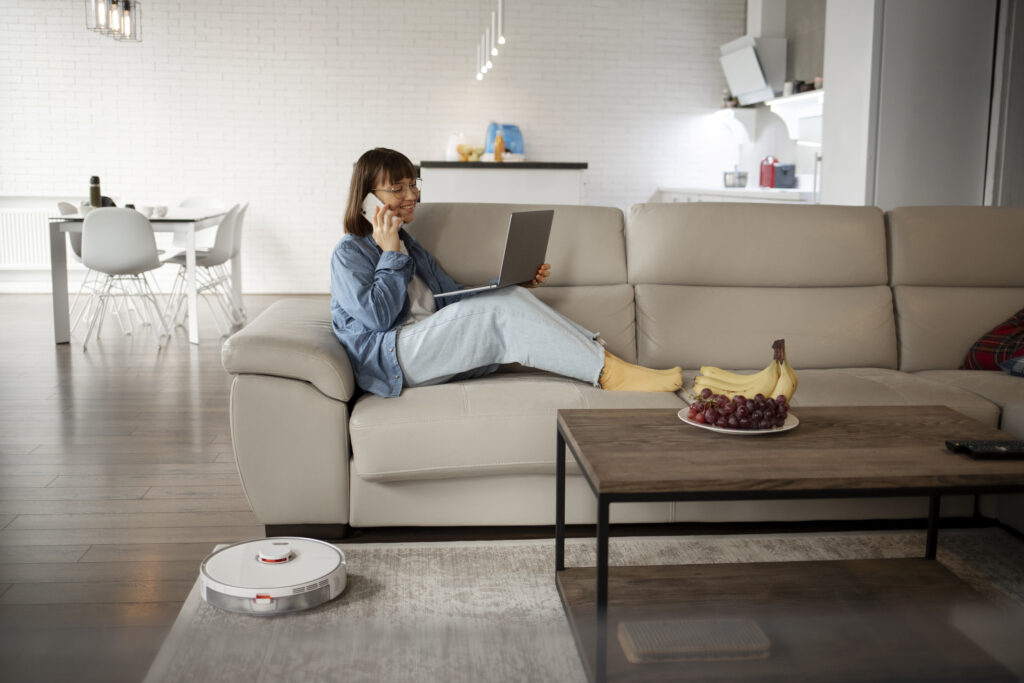 Vrouw op bank met laptop en telefoon in moderne woning – slimme energieverbruikers kiezen oplossingen van New Energy Systems na salderingsregeling
