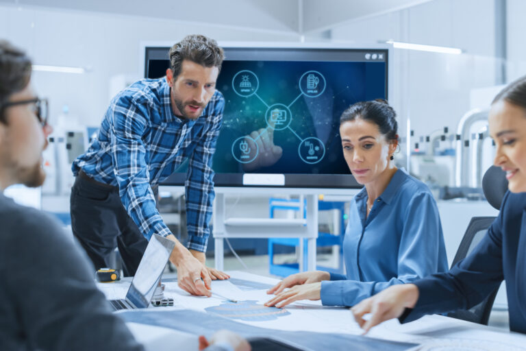 Zakelijk team bespreekt energiebeheeroplossing van New Energy Systems met EMS-dashboard op scherm – New Energy Manager in ontwikkeling