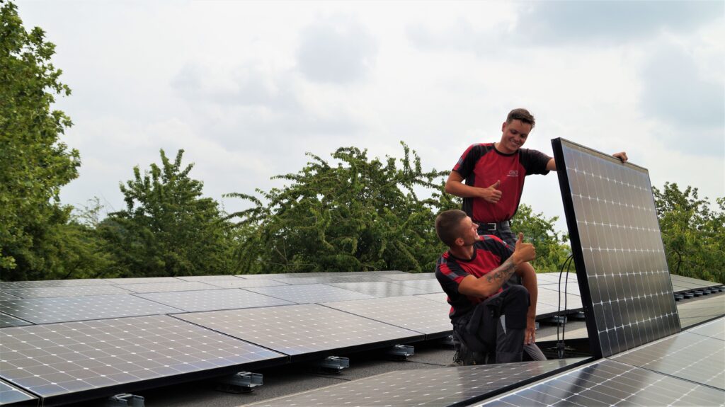Twee monteurs van New Energy Systems controleren en testen een zonnepaneelinstallatie op het dak.