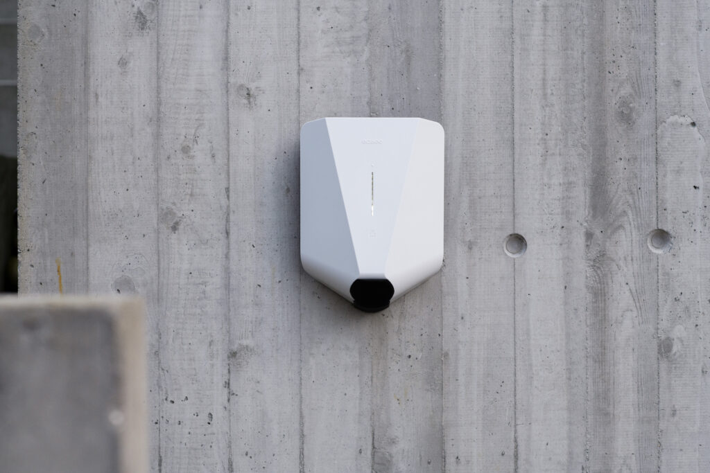 Witte Easee Home laadpaal gemonteerd op een betonnen buitenmuur.