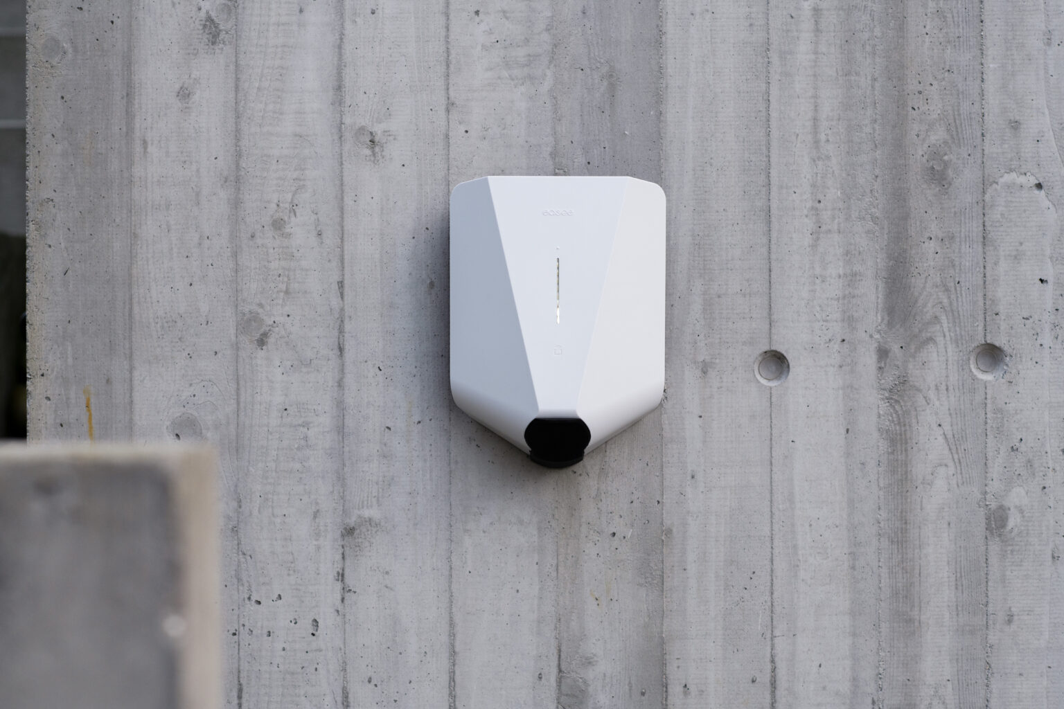 Witte Easee Home laadpaal gemonteerd op een betonnen buitenmuur.